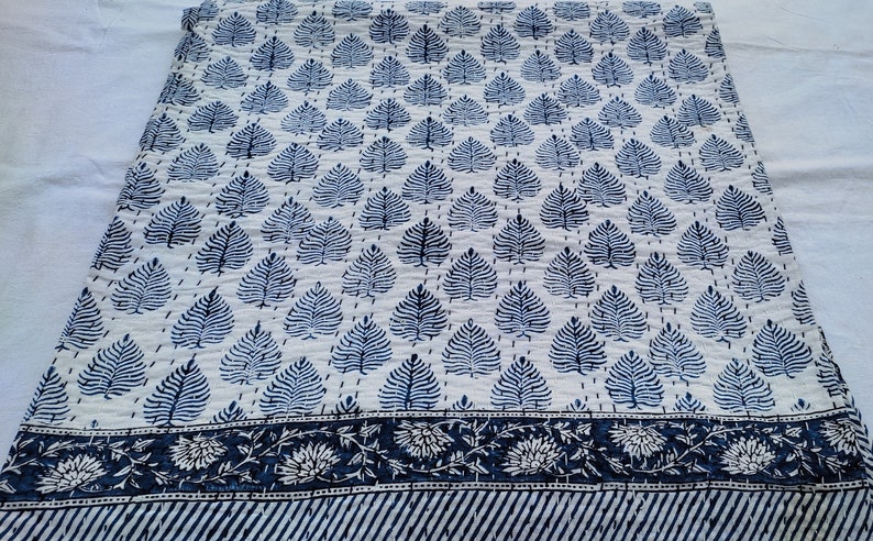 Puede incluir: Una colcha de algod&oacute;n blanco con un patr&oacute;n de hojas azules y un borde azul y blanco. La colcha est&aacute; cosida a mano y tiene un dise&ntilde;o tradicional indio.