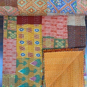 Può includere: Una trapunta patchwork caratterizzata da una varietà di pannelli rettangolari in tessuto nei toni del giallo senape, rosso scuro, marrone e verde. La trapunta è decorata con cuciture kantha bianche e presenta un lato inferiore giallo senape.