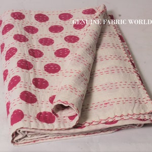 May include: White cotton quilt with a pink polka dot pattern and white stitching. The quilt is folded in half and has a "GENUINE FABRIC WORLD" label in the top right corner.