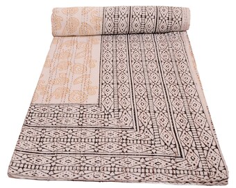 May include: A rectangular cotton quilt featuring a rolled top edge. The fabric displays a cream background with a black geometric border pattern and a section of light orange floral and animal motifs, all finished with visible running stitches.
