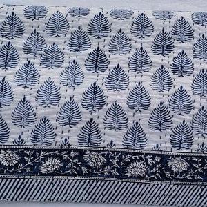 Puede incluir: Colcha de algod&oacute;n blanco con un patr&oacute;n de hojas azules y un borde azul y blanco.