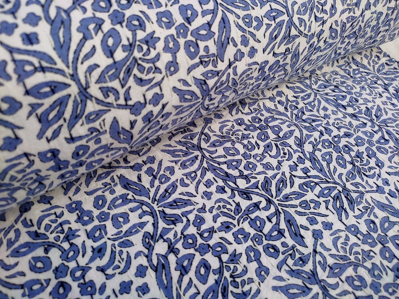 May include: White fabric with a blue floral pattern. The fabric is folded in half, showing the pattern on both sides.