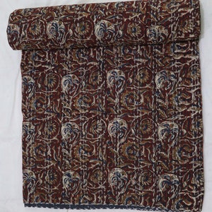 May include: A brown and cream kantha quilt with a floral pattern. The quilt is hand-stitched and has a fringed edge.