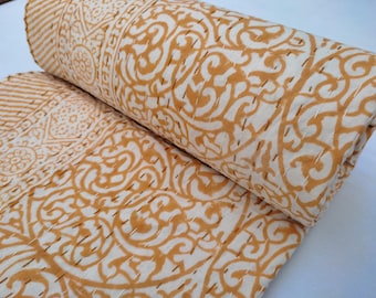 May include: A yellow and white kantha quilt with a floral pattern. The quilt is folded in half and is made of cotton.