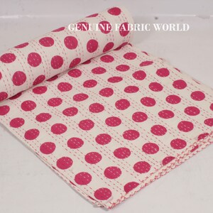 May include: White cotton kantha quilt with a pink polka dot pattern. The quilt is hand-stitched and has a fringed edge.