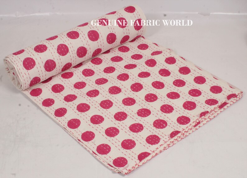 May include: White cotton kantha quilt with a pink polka dot pattern. The quilt is hand-stitched and has a fringed edge.