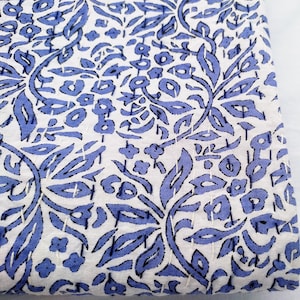 May include: White fabric with a blue floral pattern. The fabric has a subtle texture and is perfect for quilting or crafting.