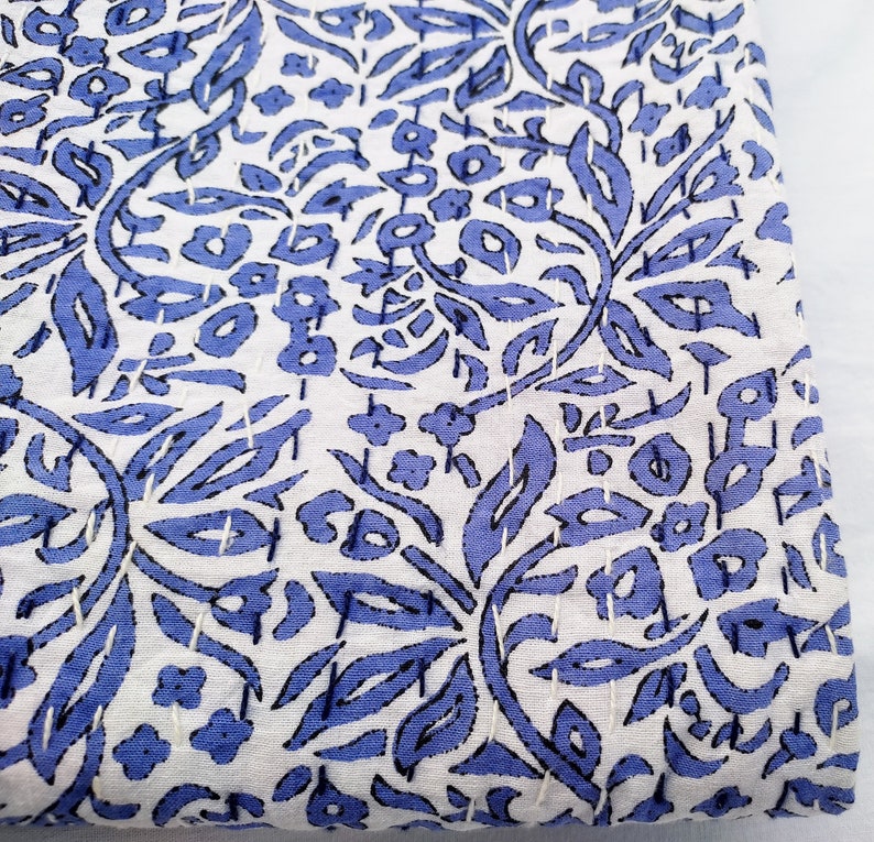 May include: White fabric with a blue floral pattern. The fabric has a subtle texture and is perfect for quilting or crafting.