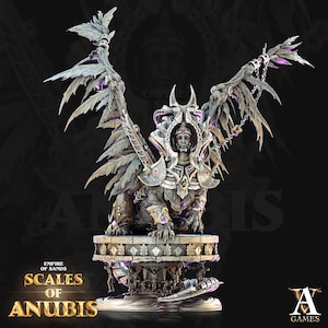 May include: A detailed, silver and gold statue of Anubis, the Egyptian god of the dead, with wings and a crown. The statue is sitting on a stone base with the words "Scales of Anubis" and "Empire of Sands" written on it. The statue is a collectible figure from the game "Anubis Games".