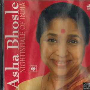 May include: A red CD case with a photo of Asha Bhosle, a famous Indian singer, on the front. The text on the case reads "Asha Bhosle Nightingale of India".
