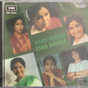May include: A CD case with a green background and a collage of photos of Asha Bhosle. The title of the album is "Many Moods Asha Bhosle" and the EMI label is visible in the top left corner.