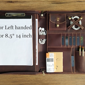 May include: Brown leather portfolio with multiple pockets and compartments. The portfolio is open and shows a notepad, pen holders, a card holder, and a zippered pocket. The text "For Left handed For 8.5* 14 inch" is written on the notepad.