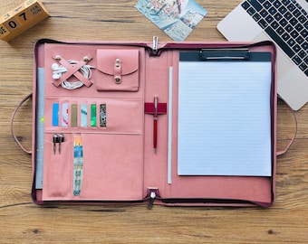 May include: A pink leather portfolio with a built-in clipboard, multiple card slots, a pen holder, and a pocket for a phone or other small items.