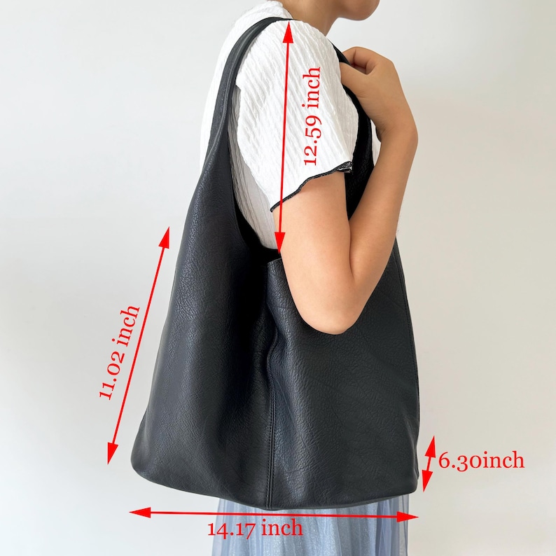 May include: Black leather tote bag with a long strap. The bag measures 14.17 inches wide, 11.02 inches tall, 6.30 inches deep, and the strap is 12.59 inches long.