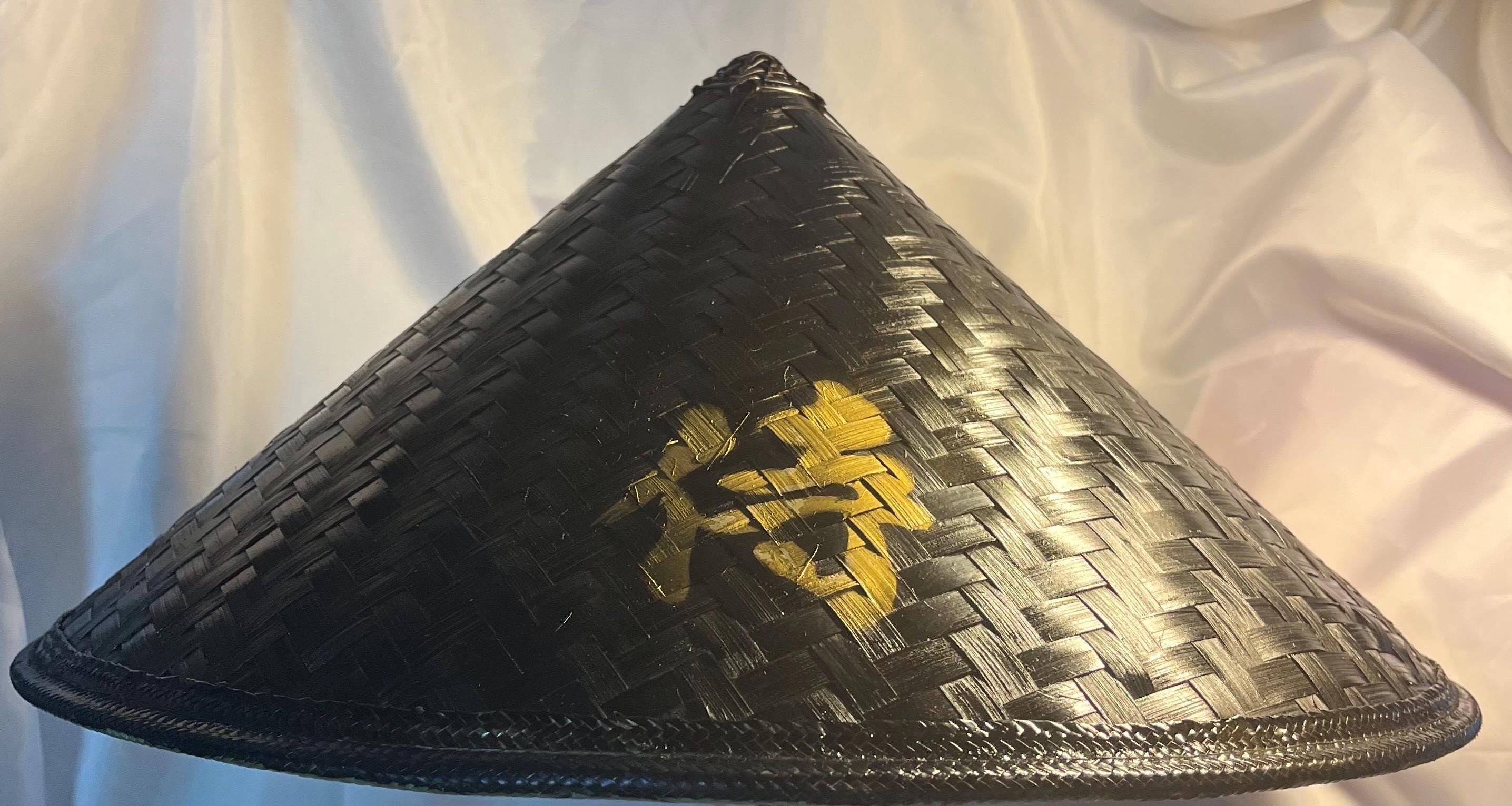 Un uomo con una maschera hannya, un kimono nero, un cappello nero con un bastone di bambù in