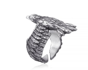 May include: A silver ring with an eagle design. The eagle's wings are spread out and the ring is open on the side.