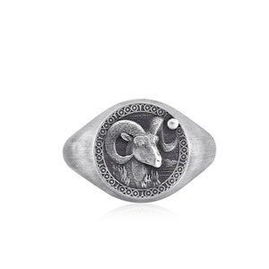 May include: A silver signet ring featuring a detailed engraving of a ram's head. The ring has a rounded oval shape and a textured finish.