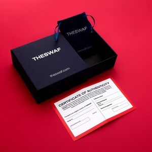 Puede incluir: Una caja negra con el texto "THESWAF" y "theswaf.com" impreso en ella. La caja est&aacute; abierta y dentro hay un certificado de autenticidad rojo y blanco. El certificado tiene el texto "CERTIFICATE OF AUTHENTICITY" y "The jewel is an original creation of THESWAF" impreso en &eacute;l.
