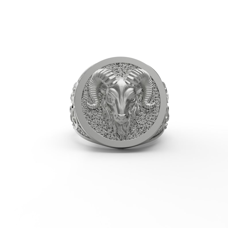 May include: A silver ring with a detailed ram head design. The ram's head is in high relief and has a textured surface.