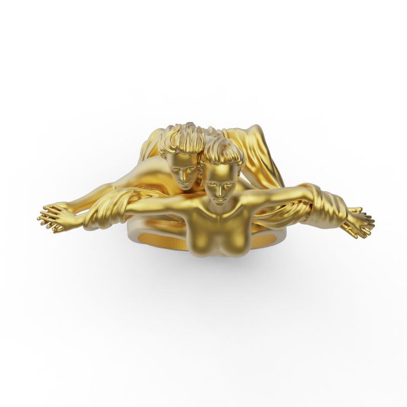 May include: A gold ring featuring a sculpted design of two figures intertwined. The figures are nude and appear to be embracing.