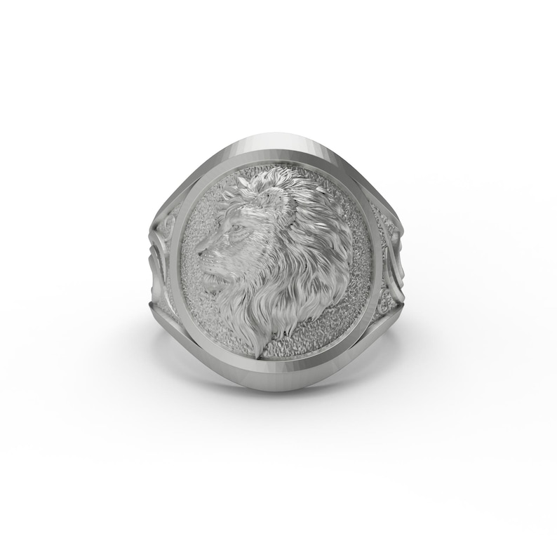 Puede incluir: Un anillo de plata con un dise&ntilde;o de cabeza de le&oacute;n. El anillo es de forma ovalada y tiene una superficie texturizada.