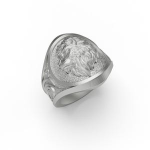 Puede incluir: Un anillo de plata con un dise&ntilde;o de cabeza de lobo. El anillo tiene una superficie texturizada detallada y una banda curva.
