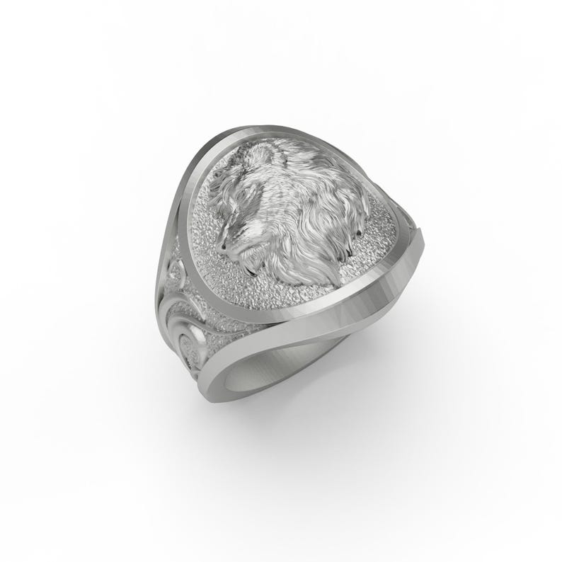 Puede incluir: Un anillo de plata con un dise&ntilde;o de cabeza de lobo. El anillo tiene una superficie texturizada detallada y una banda curva.