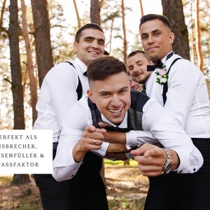 Puede incluir: Un grupo de hombres con camisas blancas y pantalones negros posan para una foto en un bosque. Un hombre est&aacute; siendo sostenido por otros dos hombres, mientras que el hombre que est&aacute; siendo sostenido apunta a la c&aacute;mara y sonr&iacute;e. El texto "PERFEKT ALS EISBRECHER. PAUSENF&Uuml;LLER & SPASSFAKTOR" es visible en la imagen.