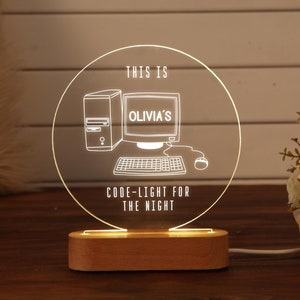 Könnte beinhalten: Ein weißes Acryl-Nachtlicht in Kreisform mit einem Computermonitor, einer Tastatur und einer Maus im Inneren. Der Text "This is Olivia's Code-Light for the Night" ist auf das Licht gedruckt.