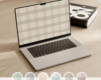 May include: A silver laptop displaying a beige and light brown plaid pattern on its screen, with the text NEUTRAL CONCEPT visible above the display. A black book with white lettering sits beside the laptop, and six circular color swatches are below.