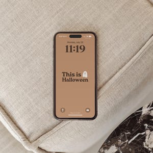 Puede incluir: Un tel&eacute;fono inteligente con un fondo marr&oacute;n y el texto "This is Halloween" con un icono de fantasma blanco. La fecha es lunes 29 de julio y la hora es 11:19.
