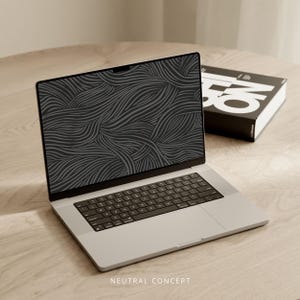 Peut inclure: Un ordinateur portable argenté avec un clavier noir et un écran noir affichant un motif abstrait noir et blanc. L'ordinateur portable est posé sur une surface en bois brun clair.