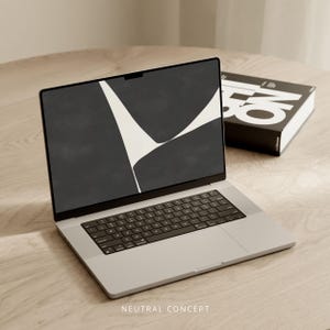 以下が含まれることがあります： 黒いキーボードと白い抽象的なデザインが施された黒い画面を持つ銀色のラップトップコンピューター。ラップトップは薄い茶色の木製の表面の上に置かれています。表面には「NEUTRAL CONCEPT」というテキストが印刷されています。