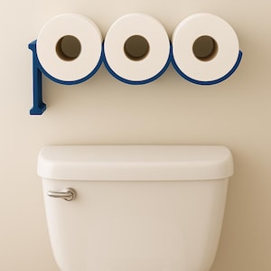 Könnte beinhalten: Eine moderne Badezimmerszene mit einer weißen Toilette unter einem blauen Toilettenpapierhalter. Der Halter ist für drei Rollen weißes Toilettenpapier ausgelegt. Die Wand ist in einem neutralen Beige gehalten.