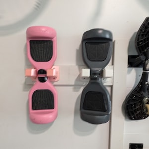 Puede incluir: Dos hoverboards montados en una pared blanca. El hoverboard de la izquierda es rosa y el hoverboard de la derecha es gris.