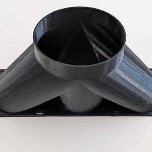 May include: A black, 3D-printed Y-shaped duct connector. The connector has a circular opening at the top and two angled openings at the bottom, all connected to a rectangular base. The object is made of a matte black material.