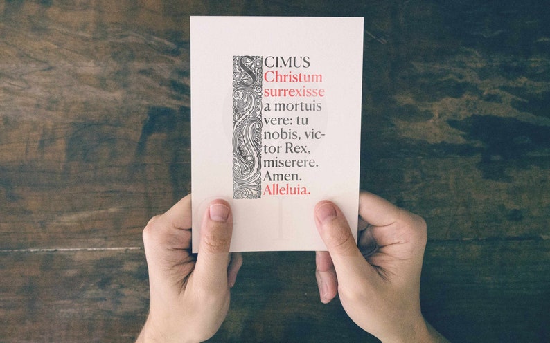 May include: A white card with black and gray decorative borders and red text that reads "CIMUS Christum surrexisse a mortuis vere: tu nobis, victor Rex, miserere. Amen. Alleluia."