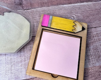 May include: A wooden note holder with a pencil design. The holder has a slot for holding notes and a pink eraser on the pencil.