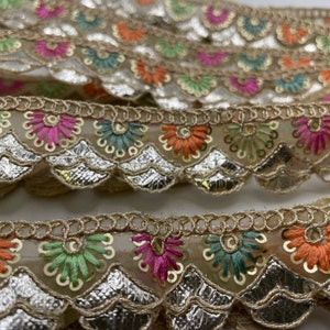 Puede incluir: Encaje con ribete dorado y borde festoneado con bordado floral de colores. El encaje es transparente y tiene un aspecto delicado y femenino.