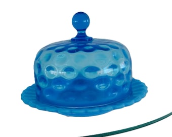 May include: A blue glass cake dome with a scalloped edge and a knob on top. The dome has a textured pattern of small bubbles.