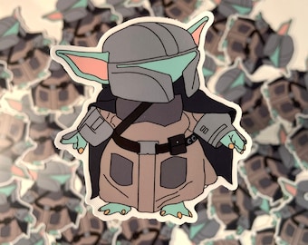 May include: A sticker of a green and gray Baby Yoda character wearing a Mandalorian helmet and armor. The character is standing with its arms outstretched and has a serious expression on its face.