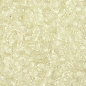 May include: A close-up image of a large quantity of small, clear glass beads. The beads are round with a hole in the center. The beads are arranged in a random pattern.