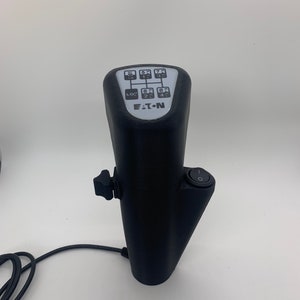 May include: Black electronic gear shifter with a white label that says "EATON" and a numbered grid of buttons. The shifter has a black cord and a black on/off switch.