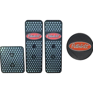 May include: A collection of black, textured accessories, comprising two long rectangular items, a square item, and a circular item. Each piece has a honeycomb design and the red and white "Peterbilt" logo.