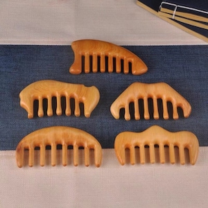Peut inclure: Six peignes en bois de différentes formes et tailles. Les peignes sont en bois brun clair et ont une finition naturelle. Ils sont tous conçus avec une poignée arrondie et ont une rangée de dents le long du dessus.