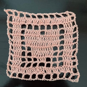 May include: A pink crocheted square with a delicate openwork pattern.