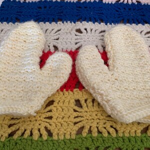 May include: A pair of white crocheted oven mitts. The mitts are made with a simple stitch pattern and have a soft, fluffy texture.