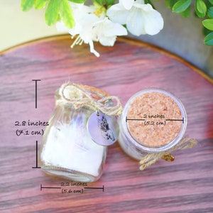 May include: Two small glass jars with cork lids and twine tied around the top. The jars are 2.8 inches tall and 2.2 inches wide. The cork lids are 2 inches in diameter.
