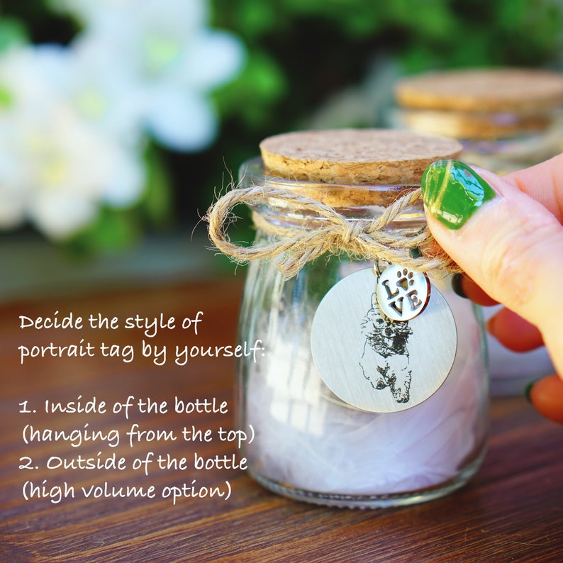 May include: A clear glass bottle with a cork stopper and a twine bow. A silver charm with a paw print and the word "LOVE" hangs from the bottle. The charm also features a black and white silhouette of a dog. The bottle is filled with white tissue paper. The text "Decide the style of portrait tag by yourself: 1. Inside of the bottle (hanging from the top) 2. Outside of the bottle (high volume option)" is visible in the image.