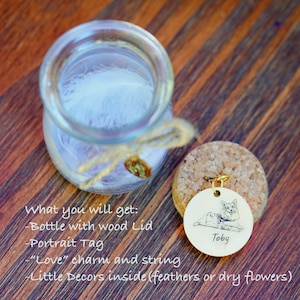 May include: A glass jar with a cork lid and a small metal tag with a pet portrait and the name "Toby". The jar contains a white feather and a small charm. The text "What you will get: -Bottle with wood Lid -Portrait Tag -"Love" charm and string -Little Decors inside (feathers or dry flowers)" is written below the jar.